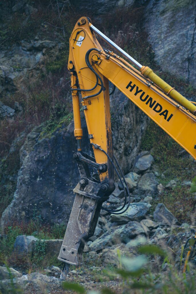 Close-up of Hyundai excavator operating in a rocky quarry setting, showcasing heavy equipment in action.