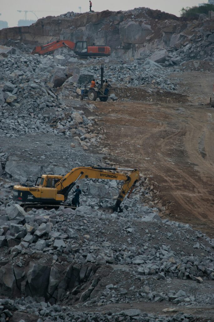 Heavy machinery working at a rocky quarry, showcasing industrial construction activity.