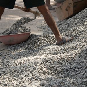 Man using a shovel to move rocks on a construction site in Bengaluru, India.